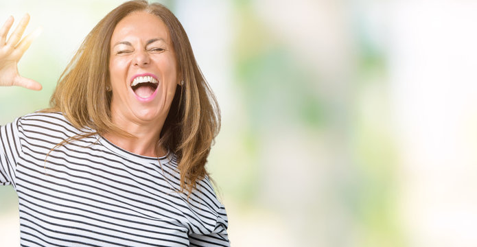 Beautiful middle age woman wearing stripes sweater over isolated background Dancing happy and cheerful, smiling moving casual and confident listening to music