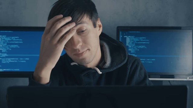 Tired computer developer and hacker is working late at night on his computer and feeling overworking, cyber security and overwork concept