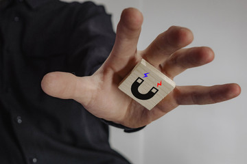 Fototapeta premium a man in a suit whose wooden cube with a picture of a magnet.