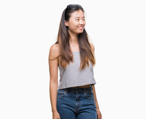 Young asian woman wearing sunglasses over isolated background looking away to side with smile on face, natural expression. Laughing confident.