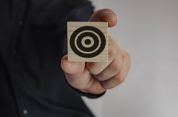 man holds in his hand a wooden cube patterned target. man holding a cube in his hand. target. aspiration