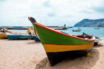 Naklejka na ściany i meble Old fishing boat on the shore. Boat with nets waiting for fishermen on the beach of Cape Verde.