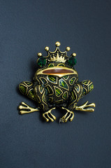 golden enamelled brooch frog wearing a crown isolated on black