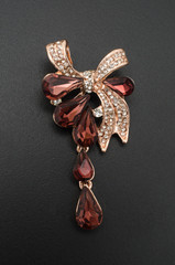 golden brooch bow with diamonds and rubies and drops isolated on black