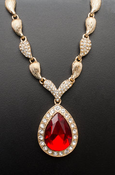 golden pendant with ruby and diamonds isolated on black macro