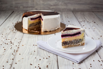 White chocolate sponge cake with fruit jelly and poppy on wooden background