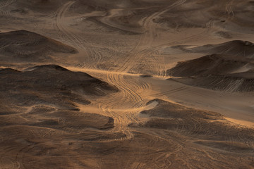 Jeep traces in the desert sand with low sunset light