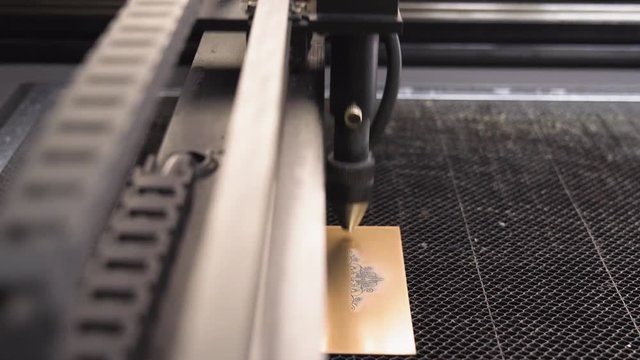 Tilt shot of a CO2 Laser Engraver while engraving a metal plate