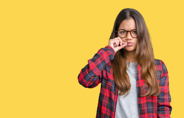 Young beautiful brunette woman wearing jacket and glasses over isolated background mouth and lips...