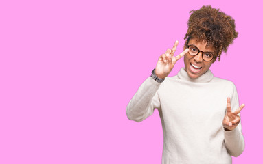 Beautiful young african american woman wearing glasses over isolated background smiling looking to the camera showing fingers doing victory sign. Number two.