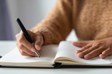 Close-up of businesswoman making notes in personal organizer. Unrecognizable lady writing in diary. Planning time concept