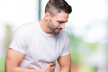 Obraz premium Young man wearing casual white t-shirt over isolated background with hand on stomach because indigestion, painful illness feeling unwell. Ache concept.
