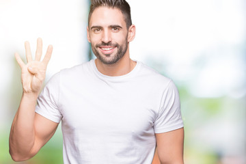 Young man wearing casual white t-shirt over isolated background showing and pointing up with fingers number four while smiling confident and happy.