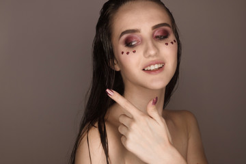 The portrait of a young girl with dark hair isolated on a brown background