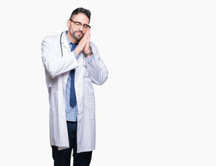 Handsome young doctor man over isolated background sleeping tired dreaming and posing with hands together while smiling with closed eyes.