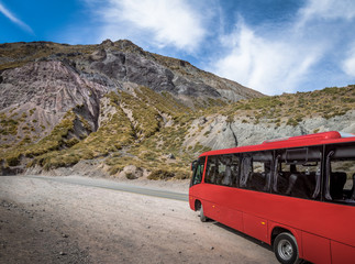 Red bus on a road at Cajon del Maipo Canyon - Chile