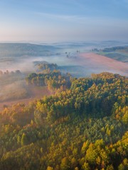 Obraz premium Antena krajobraz z mgłowym wschodem słońca nad łąkami i lasem