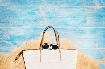 Top view of sandy beach with blue marine planks frame and summer accessories. Background with copy space and visible sand and wood texture. Border composition