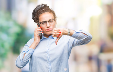 Young braided hair african american business girl showing calling using smartphone over isolated background with angry face, negative sign showing dislike with thumbs down, rejection concept