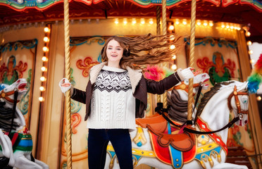 Beautiful happy woman with long vawy hair smiling over winter carousel .