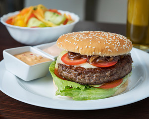 American food, Cheeseburger - Delicious burger with fries, served on a white plate on a wooden table