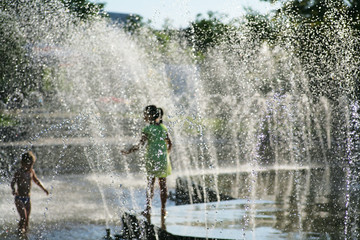 Wet summer unrecognizable  kids playing in water fountain pond.