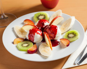 Close up view of ice cream dessert with fruits - beautifully arranged and served on a wooden table