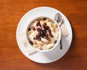 Healthy cereal breakfast bowl - oat porridge with fruits, beautifully arranged in a green bowl on a wooden table