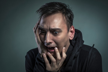 Scared young man experiencing strong fear, shivering in horror