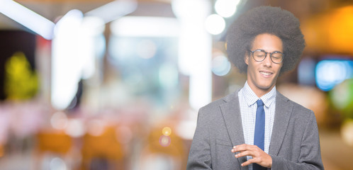 Young african american business man with afro hair wearing glasses disgusted expression, displeased and fearful doing disgust face because aversion reaction. With hands raised. Annoying concept.