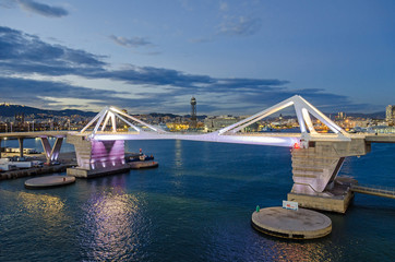  Port Vell with its bridge Porta d'Europa and the aerial tramway tower Torre Jaume I in Barcelona at night