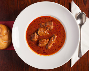 Böhmische Küche, Rindsgulasch - Köstliches Gulasch angerichtet auf einem Holztisch in weißem Teller