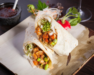Delicious healthy burrito wrap, beautifully arranged and surved on a white wooden table	