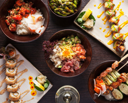 Japanese Food - Top view of differnt japanese and chinese dishes, beautifully arranged and served on a dark wooden table