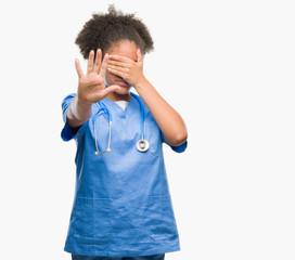 Young afro american doctor woman over isolated background covering eyes with hands and doing stop gesture with sad and fear expression. Embarrassed and negative concept.