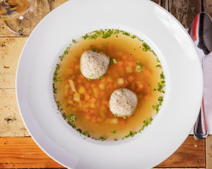 Böhmische Küche, Rindsuppe mit Leberknödel - Angerichtet auf einem Holztisch in weißem Teller
