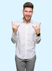 Naklejka premium Young handsome business man shouting with crazy expression doing rock symbol with hands up. Music star. Heavy concept.