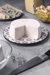 natural goat cheese and other types of cheese on gray marbled background