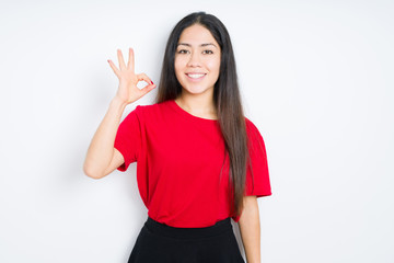 Beautiful brunette woman wearing red t-shirt over isolated background smiling positive doing ok sign with hand and fingers. Successful expression.