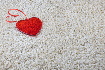  A red glass heart on a carpet love and Valentine concept. Copy space.         