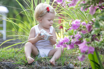 Outdoor portrait of a cute baby girl sitting in the park and playing with wooden cubes