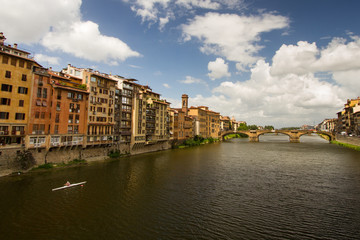 Obraz premium Morning Exercise - A lone oarsman rows along the Arno River on a beautiful summer morning. Ponte Vecchio over River Arno. Florence, Italy
