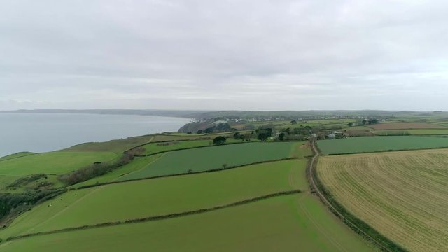 Aerial tracking over coastal farmland in the perfect English countryside. various fields for livestock and crops.