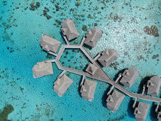 Aerial view of overwater bungalows with thatched roofs in the Moorea lagoon in French Polynesia - obrazy, fototapety, plakaty