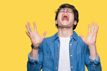 Young handsome man wearing glasses over isolated background celebrating mad and crazy for success with arms raised and closed eyes screaming excited. Winner concept