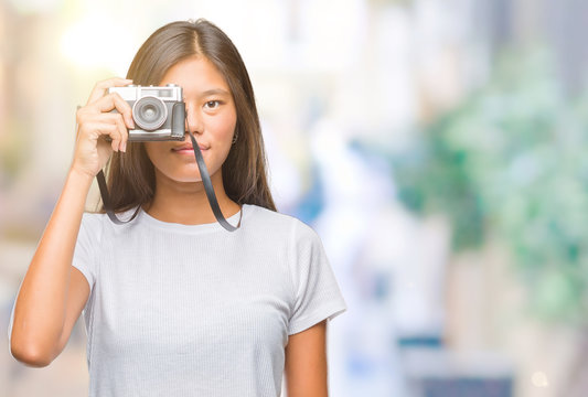 Young asian woman holding vintagera photo camera over isolated background with a confident expression on smart face thinking serious