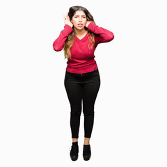 Fototapeta premium Young beautiful woman wearing red sweater Trying to hear both hands on ear gesture, curious for gossip. Hearing problem, deaf