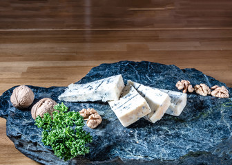 Obraz premium Cheese from France named Tommette des Alpes on the natural black stone platewith shadow