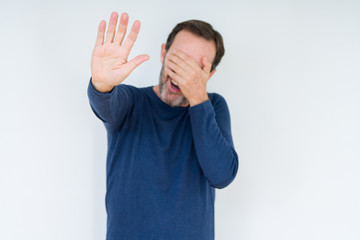 Elegant senior man over isolated background covering eyes with hands and doing stop gesture with sad and fear expression. Embarrassed and negative concept.