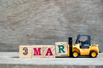 Toy forklift hold block R to complete word 3mar on wood background (Concept for calendar date 3 in...